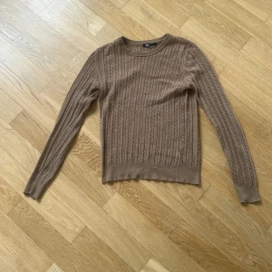 Brun kabelstickad tröja Gina Tricot - Säljer en brun kabelstickad tröja från Gina Tricot i storlek M. Tröjan har rund halsringning, långärmad passform och ribbade muddar. Ett hål i armhålan på höger sida. Hämtas i Östersund eller skickas på post.
