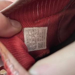 Adidas Predator fotbollsskor röd/svart - Säljer ett par Adidas Predator fotbollsskor i rött och svart med klassiska tre svarta ränder på sidan. Skorna har snörning, mönstrad ovandel och dobbar för bra grepp på planen. Perfekta för dig som vill sticka ut på matchen! Helt ok skick lite smutsiga du får betala frakt själv 