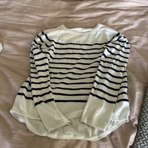 Randig vit och marinblå stickad tröja H&M - Vit tröja med blåa ränder. Tröjan har ett litet hål vid armhålan men de syns inte. 