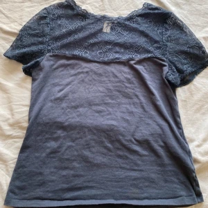 Mörkblå T-shirt med spetsdetaljer - Snygg mörkblå T-shirt med korta ärmar och vacker spets upptill.