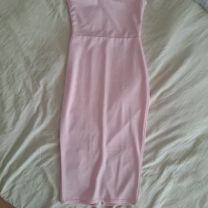 Ljusrosa one shoulder klänning PLT - Säljer en ljusrosa, figurnära långklänning från PrettyLittleThing. Klänningen har en snygg one shoulder-design och slits bak för extra rörelsefrihet. Perfekt för dig som vill sticka ut med en stilren och feminin look.