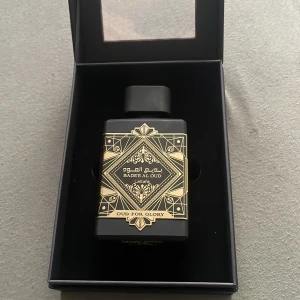 Lattafa Badee Al Oud Oud For Glory - Exklusiv parfym i svart, fyrkantig flaska med lyxiga gulddetaljer och orientaliskt mönster. Kommer i elegant svart kartong med fönster. Doften är inspirerad av oud och har en mystisk, djup vibe. Perfekt för dig som gillar unika och kraftfulla dofter. Säljer denna då jag tyckte att den inte passade min smak, jättefin lukt och unik men inget som passar mig tycker jag. Parfymen är inspirerad av ” initio Oud For Greatness”. Mycket lika tycker jag. Flaskan är 100 % full, bara tagit ett sprut. 