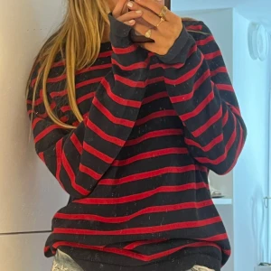 Randig stickad tröja från Lexington - Säljer en svart och röd stickad tröja från Lexington i storlek L. Tröjan har ett klassiskt randigt mönster och är långärmad med en relaxed fit. Perfekt för dig som gillar en chill och snygg stil. Materialet är mjukt och känns skönt mot huden.