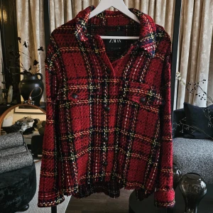Jacka från Zara - Snygg rutig overshirt från Zara i rött, svart och gult. Jackan har grov textur, klassisk krage, knappar framtill och på fickorna samt långa ärmar. Perfekt för lager-på-lager och ger en cool vibe till din outfit. Jackan är i XL men passar mindre storlekar också.
