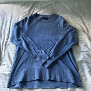 Blå stickad tröja från Lexington storlek S - En stilren blå stickad tröja med rund halsringning och långa ärmar. Tröjan har bred ribbad kant nedtill och vid ärmsluten, vilket ger en snygg och enkel look. Perfekt att matcha med jeans eller kjol för en chill vibe.