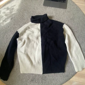 Svart och vit polotröja & Other Stories - Snygg polotröja från & Other Stories i svart och vitt blockmönster. Tröjan har hög krage, lång ärm och är stickad i mjukt material. Den är lite nopprig och den har en liten fläck på ena armen men inget man lägger märke till❤️