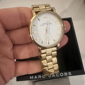 Guldig klocka från Marc Jacobs - Stilren klocka från Marc Jacobs med guldig länk. Kommer ej till användning och är i fint skick. Kontakta för fler bilder. Pris går att diskutera.