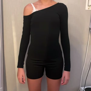 Svart offshoulder långärmad topp Shein - Svart långärmad topp från Shein i offshoulder-modell. Tight passform som sitter snyggt mot kroppen och ger en stilren look. Tillverkad i mjuk bomullsblandning med stretch. Perfekt för dig som gillar trendiga och enkla plagg.