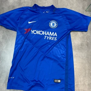 Chelsea Hazard 10 matchtröja Nike - Chelsea FCs officiella blå matchtröja från Nike med Hazard 10-tryck på ryggen. Tröjan har korta ärmar, klubbmärke och sponsortryck framtill samt Dri-FIT-material som andas.