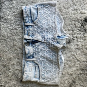 Ljusblå lowwaist mini jeansshorts med spetsdetaljer - Snygga low waist mini jeansshorts i strl 36, midja:39. Kommer fler unika jeansshorts/kjolar så följ!!