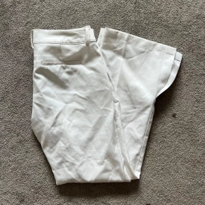 Vita lågmidjade kostymbyxor från bikbok  - Säljer dessa vita lågmidjade kostymbyxorna från bikbok med slits. De är i petite modell och passar om man är ungefär 150-160 cm lång 💕 har liten defekt, se sista bilden! Passar också xs då de är små i storleken 