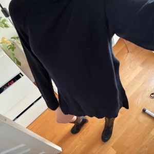 Svart stickad klänning Filippa K XS - Mysig svart stickad kortklänning från Filippa K med polokrage och långa ärmar. Perfekt för lager-på-lager och funkar lika bra med boots som sneakers. Enkel och stilren design i mjukt material. Väldigt hög slits på sidan!