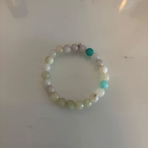 Pärlarmband i pastellfärger - Ett snyggt armband med runda pärlor i olika pastelliga nyanser av vitt, beige, ljusgrönt och turkost. Perfekt accessoar för att ge din outfit en chill och fräsch vibe. Elastiskt band gör det enkelt att ta på och av.