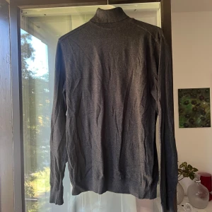 Selected polotröja i bomull - Mörkgrå polotröja med ribbad krage och muddar. Tröjan är långärmad och har en clean, klassisk look som funkar till många olika stilar. Tillverkad i mjuk bomull som känns skön mot huden. Perfekt för lager-på-lager under kyliga dagar.