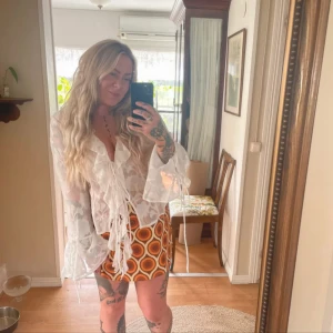 Retro kortkjol cider 70s 70tal  - Supercool kortkjol med retroinspirerat cirkelmönster i brunt, orange och vitt. Kjolen har en klassisk A-linjeform och är perfekt för dig som vill sticka ut. Materialet känns som polyester och den har en normal passform. Perfekt för att skapa en unik look!