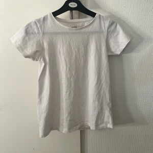 Vit basic t-shirt från 157 - Enkel och stilren vit t-shirt från 157 med rund hals och korta ärmar. Tillverkad i mjuk bomull med lite stretch för extra komfort. Perfekt att matcha med jeans eller shorts för en clean look.