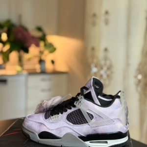 Nike Air Jordan 4 Retro 'Zen Master' lila - Nike Air Jordan 4 Retro 'Zen Master' med unik lila och grå canvas-överdel, svarta meshpaneler och detaljer i transparent plast. Snygg svart och grå sula med vit midsole och klassisk Jumpman-logga på hälen. Perfekt för dig som vill sticka ut med dina sneakers.