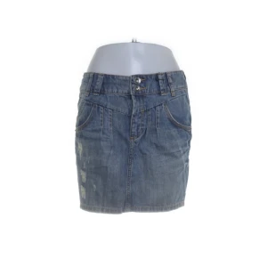 Blå jeanskjol från QS, storlek 36 - Midjemått 40cm.                                                       Snygg blå jeanskjol från QS i klassisk femficksmodell. Kjolen är kort, har slitna detaljer framtill och coola bakfickor med broderi. Gjord i 100% bomull för en skön och avslappnad känsla. Perfekt till sneakers eller boots för en casual look.