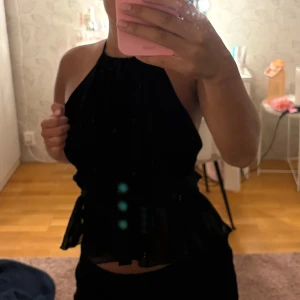 Svart topp med snören baktill!  - Säljer denna svarta topp med ”volanger” och snören baktill. Super fin! 