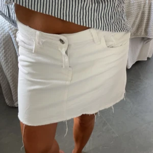 Vit jeanskjol - Snygg vit kort jeanskjol, fransig kant nertill och  fickor fram. Perfekt till sommaren och enkel att matcha med allt. 