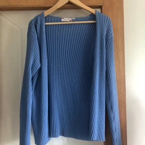 Blå ribbad kofta från Olé - Säljer en blå ribbstickad kofta från Olé i storlek L. Koftan har lång ärm, öppen framtill och är gjord i ett mjukt stickat material. Perfekt att slänga över en t-shirt eller linne för en chill och snygg look.💕🌸❣️