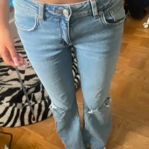 Bootcut ljusblå jeans från 157 - Ljusblå jeans från 157 med bootcut passform och slitna detaljer vid knäna. Klassisk femficksmodell med normal midja och dragkedja. Perfekta för en avslappnad och trendig look.