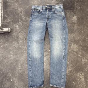 Arket Park Cropped jeans blå 28/30 - Snygga blå jeans från Arket i modellen Park Cropped. Jeansen har rak passform, klassisk femficksdesign och är tillverkade av 80% ekologisk bomull och 40% återvunnen bomull. Ljus tvätt med slitningar på låren och croppad längd för en modern vibe.