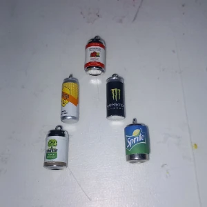 Halsbandshängen i form av läskburkar - Fem coola halsbandshängen som ser ut som små burkar av Monster, Sprite, Somersby, Rekorderlig och en gul dryck. Perfekt för dig som vill sticka ut med roliga och färgglada accessoarer. Hängena är i silverfärgad metall med detaljerade etiketter.
