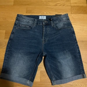 Blå jeansshorts från Only & Sons - Snygga blå jeansshorts från Only & Sons med klassisk femficksdesign och uppvikta benslut. Shortsen har en normal passform och är tillverkade i slitstarkt denimtyg. Perfekta för sommardagar när du vill ha en avslappnad och cool stil.