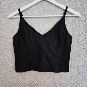 Svart skinnlook-linne från ZARA – S crop top - Supersnyggt och sexigt svart linne / crop top från ZARA, i storlek S, i skinnliknande material. Modellen är Cropped. Toppen är i riktigt bra skick och är använd försiktigt bara några få gånger. Har justerbara axelband och en v-ringning framtill som framhäver kroppen på ett smickrande sätt. Linnet har även en dold dragkedja i sidan, vilket gör det enkelt att ta på och av.  💌 Hör av dig vid frågor eller om du vill ha fler bilder! Kom gärna med egna bud 💓 Jag accepterar de flesta! Skickar snabbt!💕