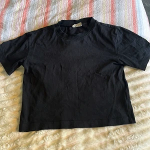 Svart croppad t-shirt från Gina tricot XS - En svart, enkel och croppad t shirt från Gina tricot. T-shirten har rund halsringning och korta ärmar. Perfekt till jeans eller kjol för en clean och avslappnad look.