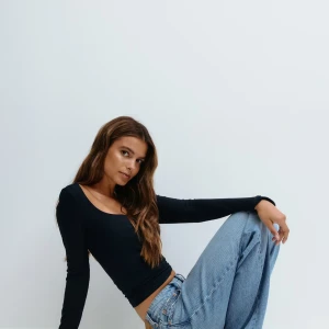 Svart långärmad topp Gina Tricot - En svart långärmad topp med utsvängda armar från Gina Tricot med rundad, djup urringning. Modellen är figurnära och enkel, perfekt att styla med jeans eller kjol. Tunt och stretchigt material som känns skönt mot huden.