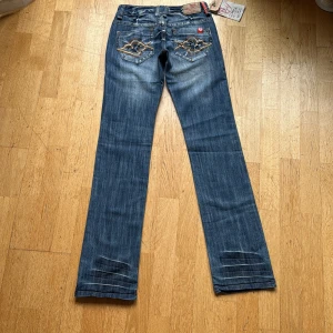 Blå jeans från Big Mantis med brodyr - Snygga blå jeans från Big Mantis som är low waisted och bootcut. Dom är oanvända med lappen kvar. Pris kan diskuteras