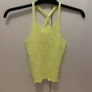 Gul smockad linnetopp från Lindex - Supersöt ljusgul linnetopp från Lindex med smockad framsida och smala axelband som korsas i ryggen. Toppen har vågig kant nertill och är perfekt för varma dagar. Mjuk och stretchig känsla, passar dig som gillar färg och enkel stil. Använd få gånger ❣️