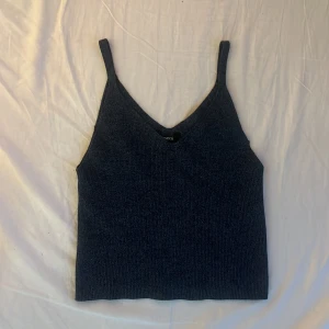 Mörkblå stickad linnetopp från Lindex - Snygg mörkblå stickad linnetopp från Lindex med smala axelband och v-ringning. Toppen har en enkel och stilren design som är lätt att matcha med olika outfits. Perfekt för dig som gillar en chill och trendig look. Nypris 249 kr.