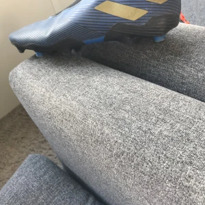 Adidas Nemesis blå fotbollsskor - Säljer ett par Adidas Nemesis fotbollsskor i blått med svarta och guldiga detaljer. Skorna har en strumpliknande passform och mönstrad ovandel för extra grepp. Perfekta för dig som vill sticka ut på planen med stilrena och sportiga skor.