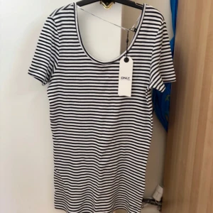 Randig kortklänning från ONLY - Snygg kortklänning från ONLY med svartvita horisontella ränder. Klänningen har rund halsringning och korta ärmar. Perfekt för en avslappnad och trendig look. Materialet är mjukt och bekvämt, troligtvis bomull.