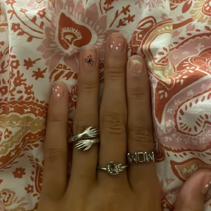 Tre coola silvriga ringar - Säljer tre unika silvriga ringar: en med två händer som möts, en med en måne och stjärnor samt en med texten 'WOW'. 45 kronor styck eller alla för 125 kr. Skriv vilken ni vill köpa! Pris går att diskutera!