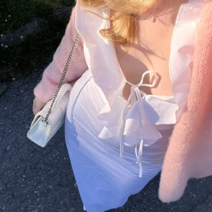 Vit långklänning med volang från Zara, perfekt midsommarklänning - En så snygg vit långklänning med volang upptill, från Zara och använd två tillfällen 🌸 knyte uppe vid bysten och figursydd. Stl 34/xs. Helt perfekt midsommarklänning/sommarklänning. Slutsåld på hemsidan, säljs inte längre.