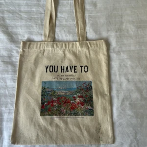 Beige tygkasse med tryck och motiv - Kvaliten på bilderna var inte helt perfekt ❤️En beige shoppingväska i bomull med långa handtag. Framsidan har ett tryck med texten 'YOU HAVE TO believe in yourself THAT'S THE SECRET OF SUCCESS' och ett färgglatt motiv av en blomsteräng vid havet. Perfekt för att bära böcker, laptop eller matvaror.
