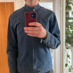 Jeansjacka från Our Legacy, blå - Säljer en tunn blå jeansjacka i storlek 48 från Our Legacy, perfekt nu till sommaren. Alla knappar och dragkedjor är i toppskick. Den enda defekten är några små skador omkring vänster axel (se bild 5). Säljer då den är lite för liten för mig. Jag är 184. 