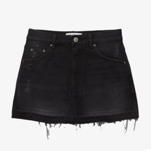 Svart jeanskjol  - Svart kort jeanskjol med rå fransig nederkant och slitna detaljer. Klassisk femficksmodell med knapp och dragkedja framtill. Perfekt för en avslappnad och cool stil.