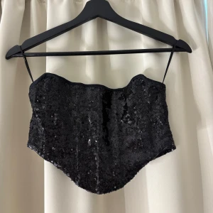 fest topp - Supersnygg svart korsett med glittriga paljetter och korsad snörning på ryggen, perfekt för festligheter. Om fler bilder önskas eller vid frågor kontakta mig💋
