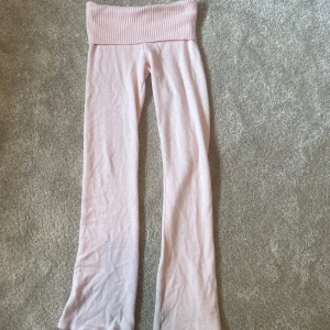 Ljusrosa mjukisbyxor från Gina Tricot - Supermysiga ljusrosa mjukisbyxor från Gina Tricot med bred ribbad midja. Byxorna har raka ben och är gjorda i ett mjukt material som känns skönt mot huden. Perfekta för chill dagar hemma eller när du vill vara extra bekväm.