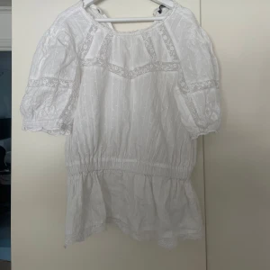 Vit blus med spets från Zara - Superfin vit blus från Zara med broderade detaljer och spetsinslag. Blusen har korta puffärmar, resår i midjan och volang nertill. 🌸💗