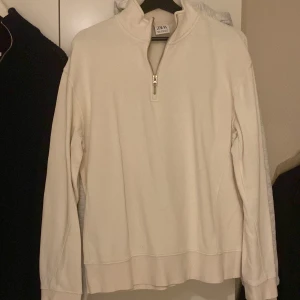 Vit half zip tröja från Zara - Säljer en stilren vit långärmad tröja från Zara med half zip-dragkedja och hög krage. Tröjan är i mjuk bomull och har en clean look som passar perfekt till jeans eller mjukisbyxor. Enkel att matcha och superbekväm för alla tillfällen.