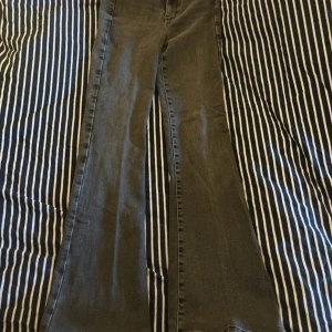 Gråa bootcut jeans från Gina Tricot - Snygga grå jeans från Gina med bootcut-modell och hög midja. Klassisk femficksdesign, dragkedja och knapp framtill. Jeansen har en cool, lite tvättad look och är tillverkade i mjukt denimtyg som sitter skönt hela dagen. Jeansen är uppsydda i anklarna med symaskin. 