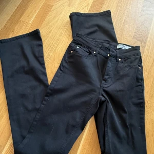 Svarta bootcut jeans från VeroModa - Svarta jeans från VeroModa med bootcut-modell. Klassisk femficksdesign, normalhög midja och raka ben som släpper ut nedtill. Jeansen är i stretchigt bomullsmaterial och har silverfärgade nitar och knapp. STORLEK S/34, aldrig använda! 