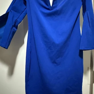 Kornblå klänning med v-ringning - Snygg kornblå klänning med v-ringad hals och vida trekvartsärmar. Enkel och stilren design som ger ett modernt intryck. Mjuk och skön känsla i materialet, perfekt för dig som gillar färg och vill sticka ut. Bilden gör att det inte ser så bra ut MEN den är väldigt väldigt vacker på💙 och THIGHT!