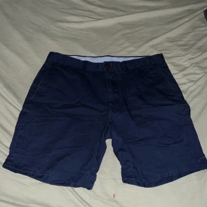Marinblå shorts Polo Ralph Lauren - Snygga marinblå shorts från Polo Ralph Lauren i klassisk passform. Tillverkade av 60% bomull och 40% pima bomull för en mjuk och skön känsla. Shortsen har sidofickor, bakfickor med knapp och bälteshällor. Perfekta för sommardagar och chill häng.